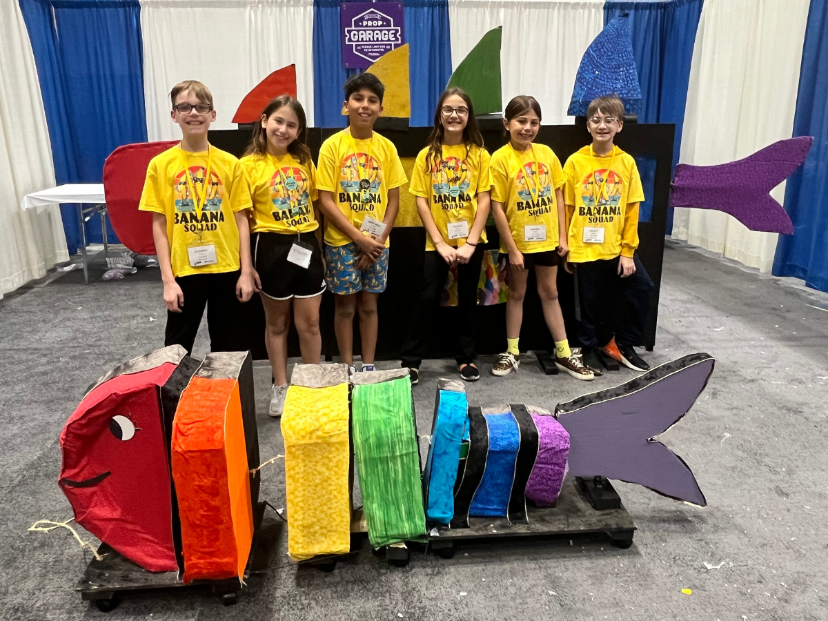 Destination Imagination team, Banana Squad, pose with a large, colorful, kinetic fish they designed as part of their solution.