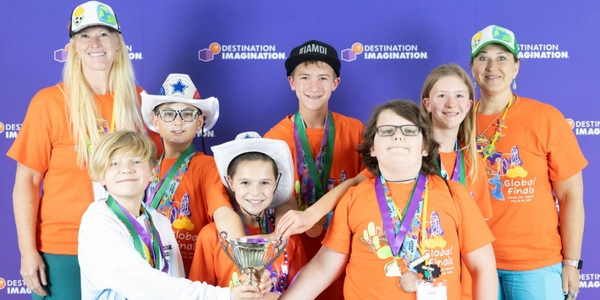 Team DI MAXION, from Texas, wearing matching orange DI shirts and posing for a photo with their trophy at Global Finals 2025. 