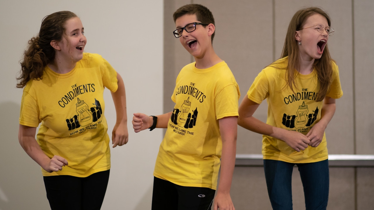 A Destination Imagination improv teams, wearing matching yellow shorts, performs at Global Finals.