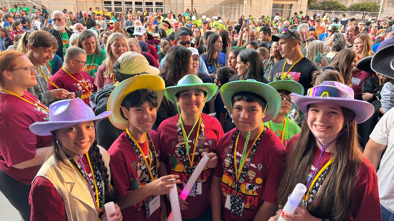 A Destination Imagination team wearing colorful hats poses for a photo at Global Finals 2023.