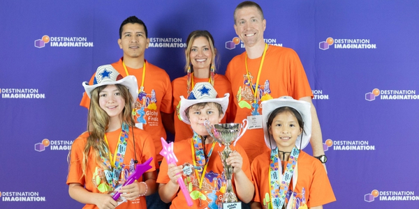 DI team, Galatas Greyhounds Tech, wearing matching orange DI Texas team shirts and holding their Global Finals 2025 trophy. 