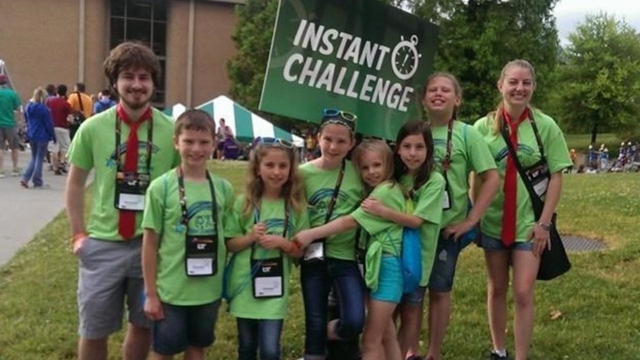 A Destination Imagination team at Global Finals 2015 holds up an Instant Challenge sign.