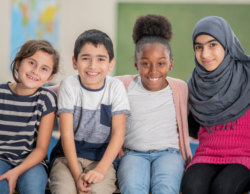 Four students sitting in a classroom looking forward and smiling